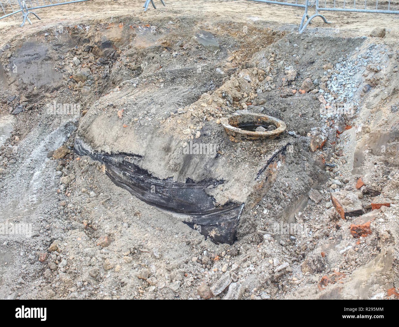 Vecchio tombino fognario contemplati nel suolo sulla costruzione di lato. Coperchio di fognatura su strada nella città. Foto Stock