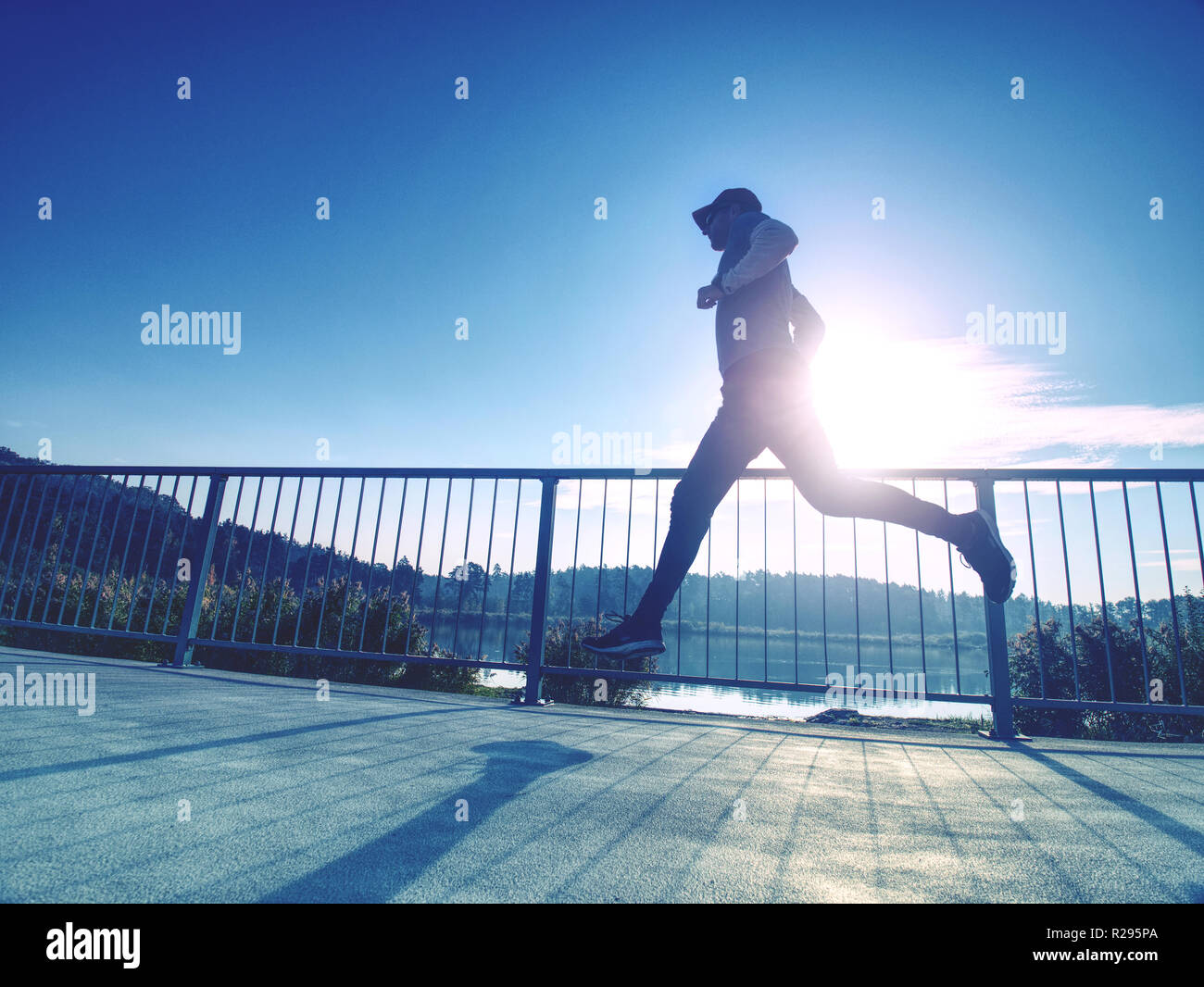 Uomo sportivo eseguito fino al ponte . Sport e stile di vita concetto - slim uomo in esecuzione oltre il ponte della città. Runner che lavora fuori all'aperto Foto Stock