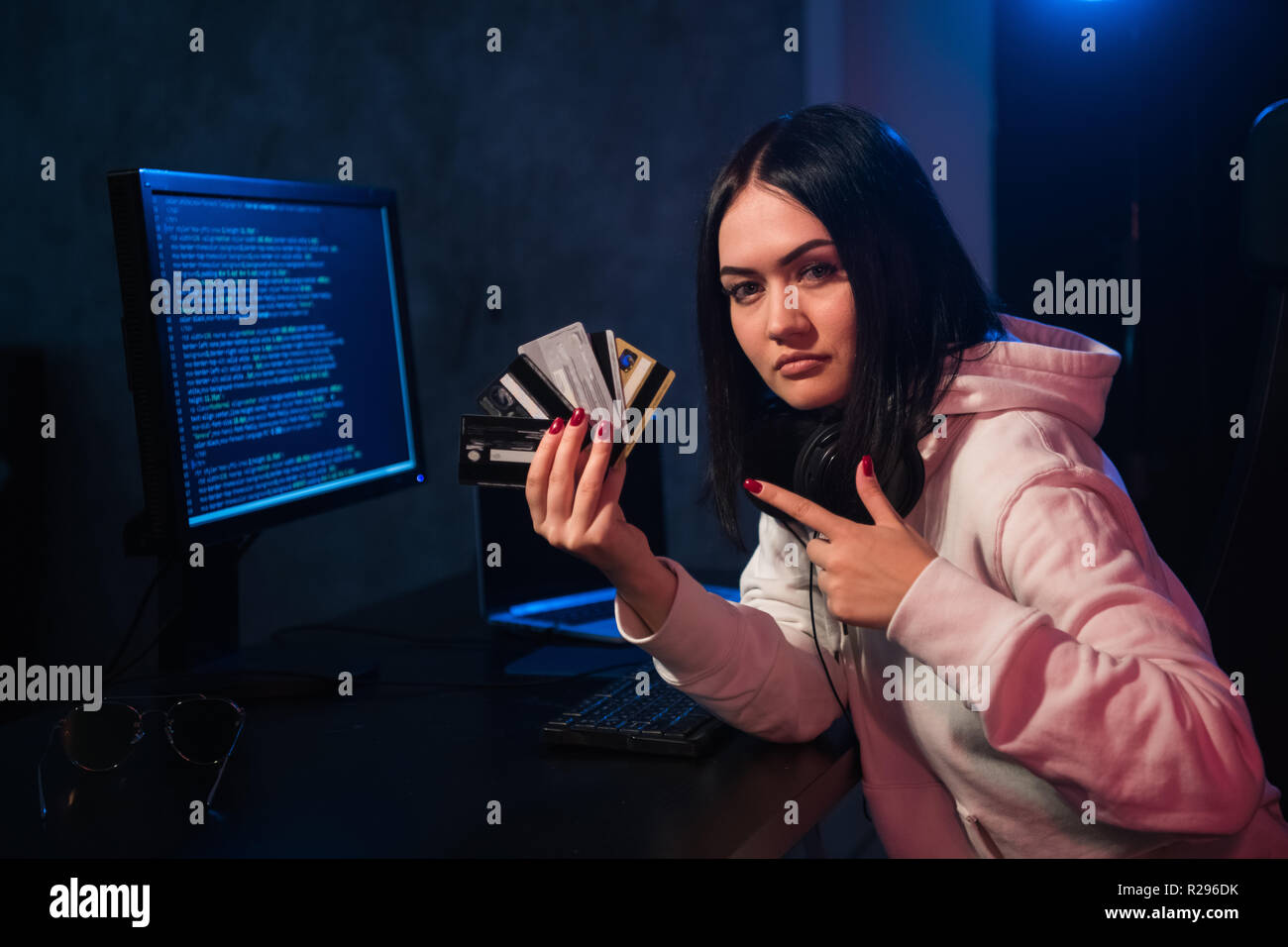 Adolescente hacker ragazza felpa con cappuccio in azienda carta di credito violare la password privata tenendo la carta di credito in criminalità informatica e criminalità informatica concetto e inte Foto Stock