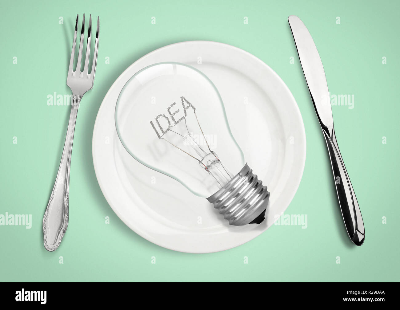 Presente idea fresca concetto. Lampadina della luce sulla piastra con cucchiaio e forchetta. Foto Stock