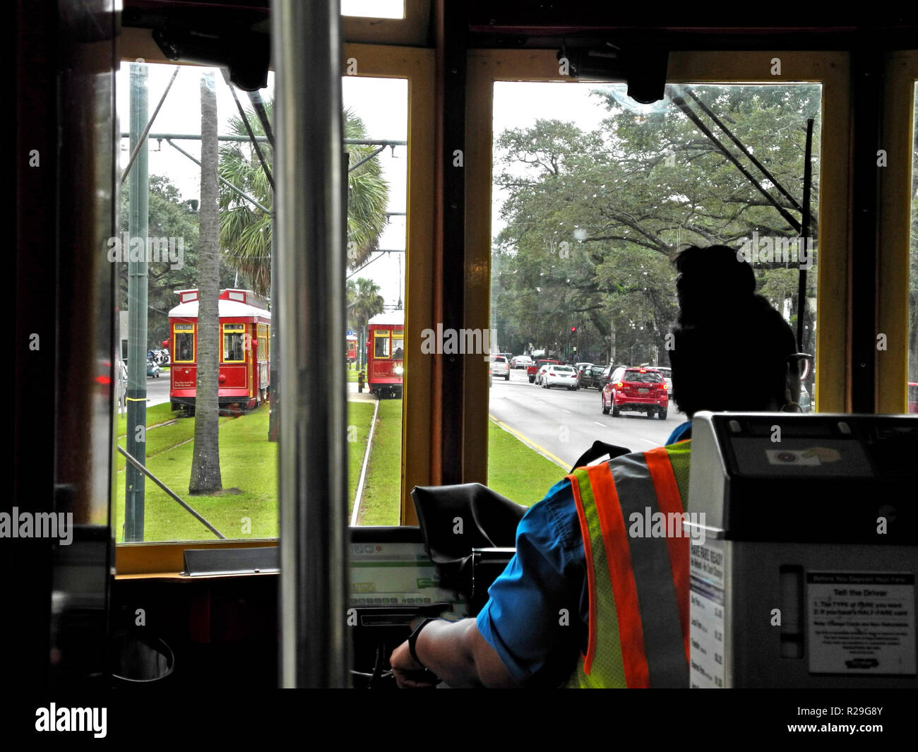 All'interno di un tram guardando oltre il self-service di biglietteria di macchina e la femmina del conducente di tale storico dei veicoli elettrici che sono state la prestazione del servizio pubblico di trasporto su rotaie di acciaio in tutto il sud della città di New Orleans, in Louisiana, Stati Uniti d'America, per più di un secolo. Venticinque chilometri di pista di ospitare quattro linee di tram, tra cui la mitica San Carlo linea che ha avviato il servizio in 1835 ed è il più antico a funzionamento continuo Streetcar linea nel mondo. L'auto rosse visto qui viaggio attraverso il cuore della città sul Canal Street e la linea dura circa trenta minuti di tragitto da estremità a estremità. Foto Stock