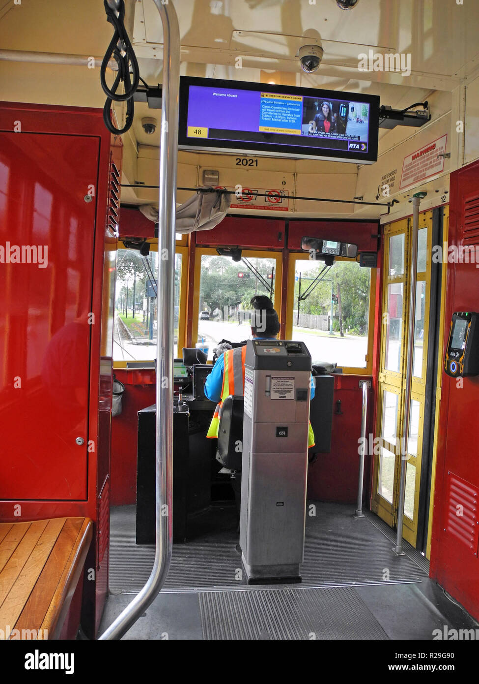 All'interno di un tram guardando oltre il self-service di biglietteria di macchina e la femmina del conducente di tale storico dei veicoli elettrici che sono state la prestazione del servizio pubblico di trasporto su rotaie di acciaio in tutto il sud della città di New Orleans, in Louisiana, Stati Uniti d'America, per più di un secolo. Venticinque chilometri di pista di ospitare quattro linee di tram, tra cui la mitica San Carlo linea che ha avviato il servizio in 1835 ed è il più antico a funzionamento continuo Streetcar linea nel mondo. L'auto rossa visto qui viaggia attraverso il cuore della città sul Canal Street e la linea dura circa trenta minuti di tragitto da estremità a estremità. Foto Stock