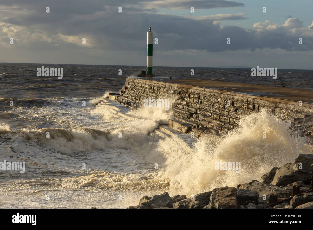 Pontile in pietra all'ingresso di Aberystwyth Harbour essendo martoriata da mare mosso. Foto Stock