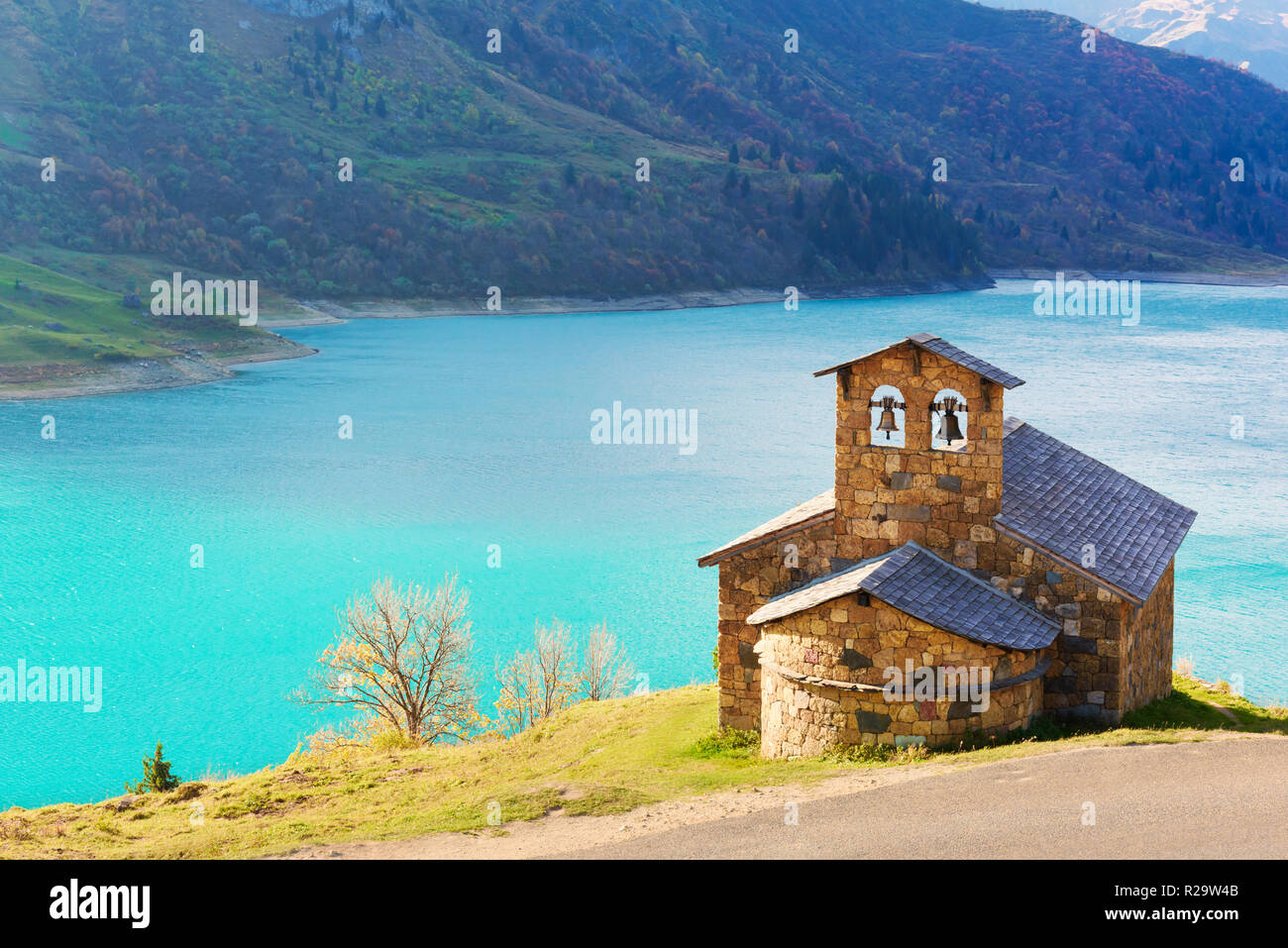 Sunny vista pittoresca della cappella di pietra sul lago di Roselend (Lac de Roselend) in Francia Alpi (Auvergne-Rhone-Alpes). Fotografia di paesaggi Foto Stock
