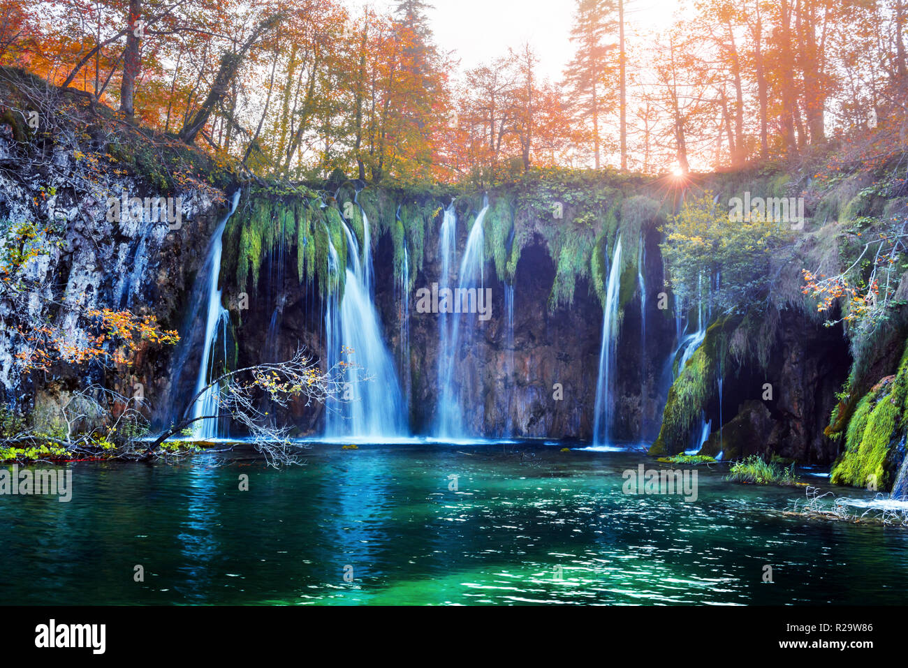Incredibile cascata con pura acqua blu nel Parco Nazionale dei laghi di Plitvice. Orange autunno foresta sul background. Il parco nazionale di Plitvice, Croazia. Fotografia di paesaggi Foto Stock