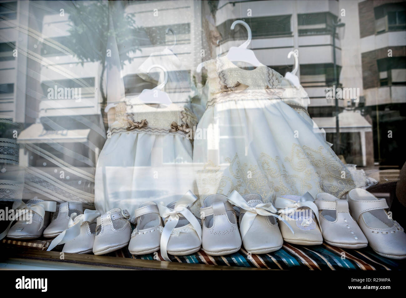 Abiti e scarpe per fare la prima comunione riflessa nella vetrina, immagine  concettuale Foto stock - Alamy