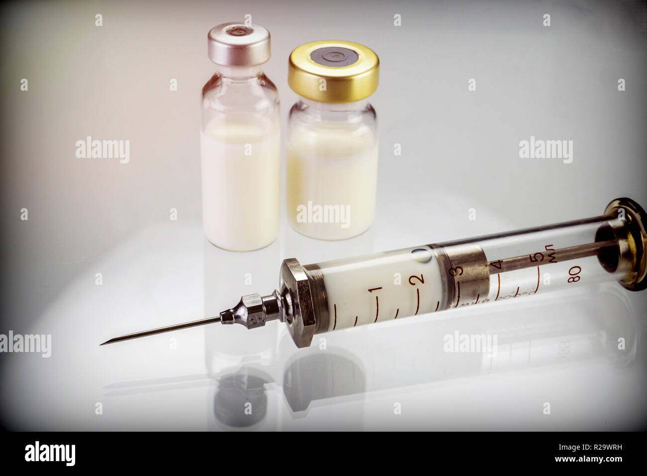 Siringa vintage accanto a due flaconi con la medicina isolati su sfondo bianco, immagine concettuale Foto Stock