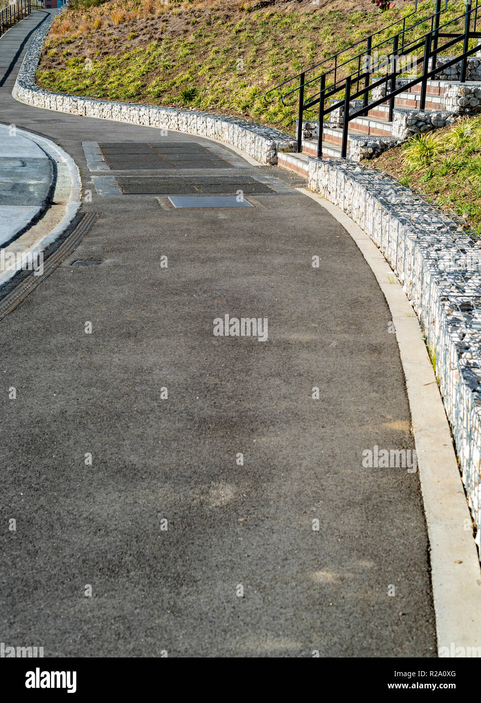 Gabbione pareti contribuendo a prevenire la frana di alcuni molto ripido terreno, a fianco di un incurvamento di sentiero. Foto Stock