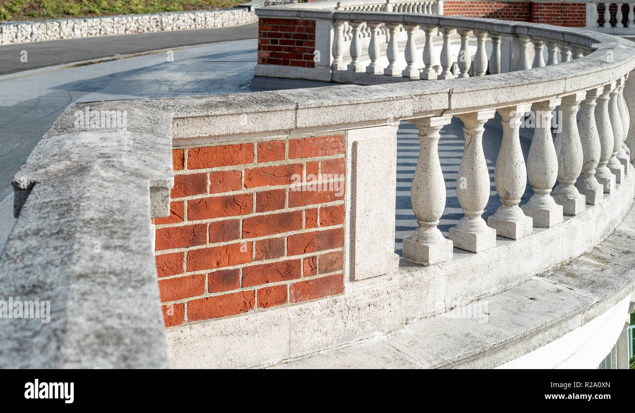 Vintage curvo balaustra in pietra, con incappucciamento di pietra e mattoni rossi. Foto Stock