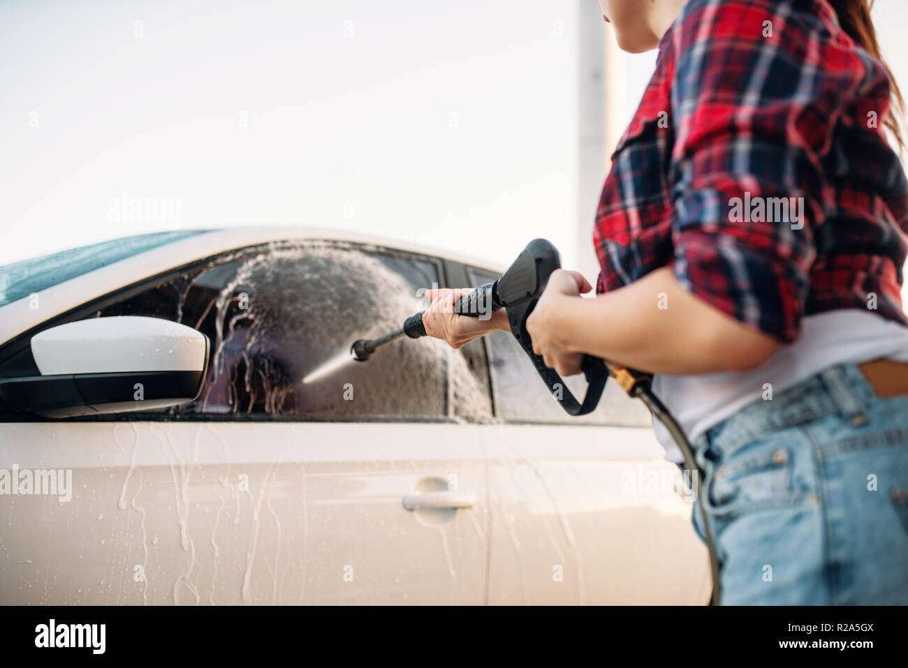 Persona di sesso femminile lavare la schiuma dal vetro auto. Donna sul  self-service di lavaggio di automobile. Esterno la pulizia del veicolo al  giorno di estate Foto stock - Alamy
