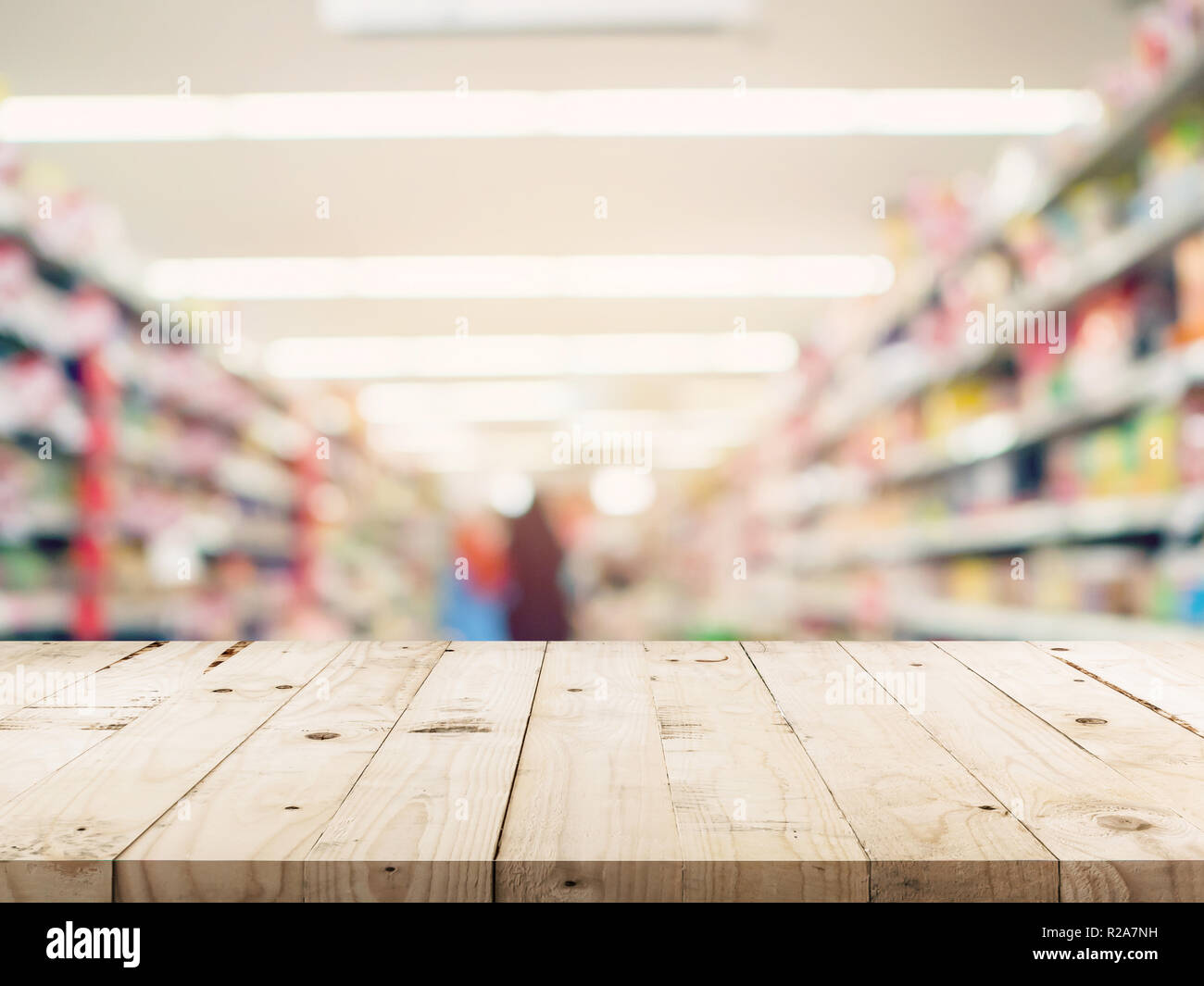 Svuotare tavolo in legno e di sfocare lo sfondo immagine. supermercato la sfocatura dello sfondo con spazio di montaggio del display per il prodotto. Foto Stock