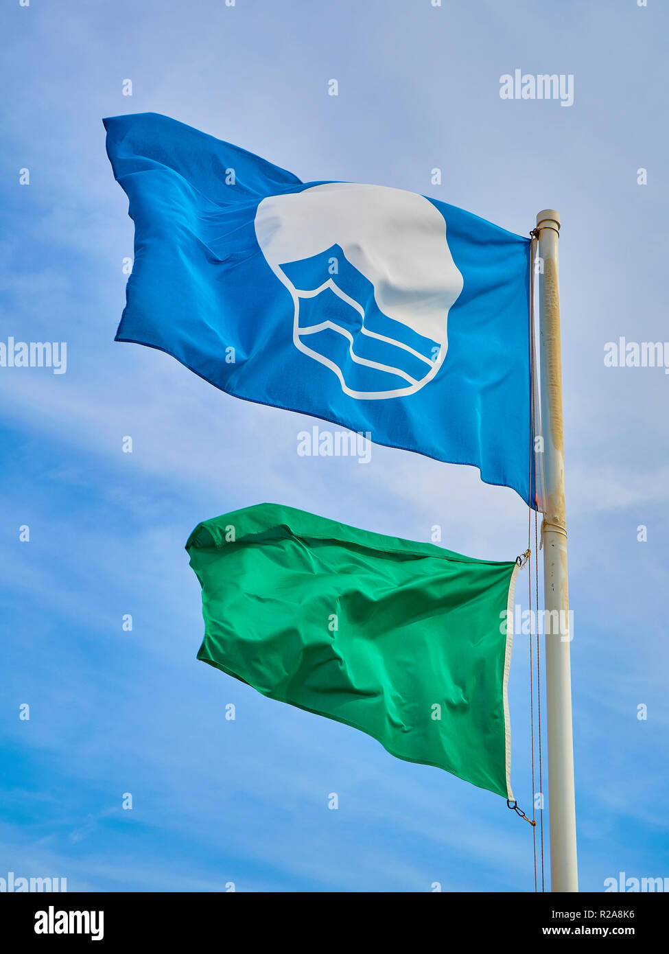 Il pagamento spiaggia Bandiera Blu e un bagnino verde bandiera su un cielo blu sullo sfondo. Foto Stock