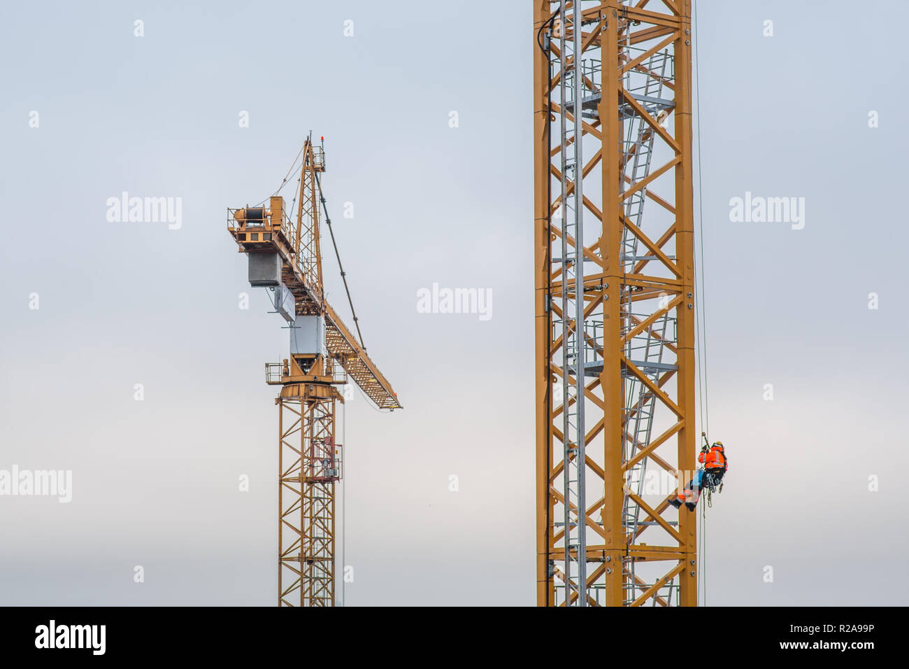 Operaio edile arrampicata su una gru alti in un freddo pomeriggio autunnale in Scandinavia. Foto Stock