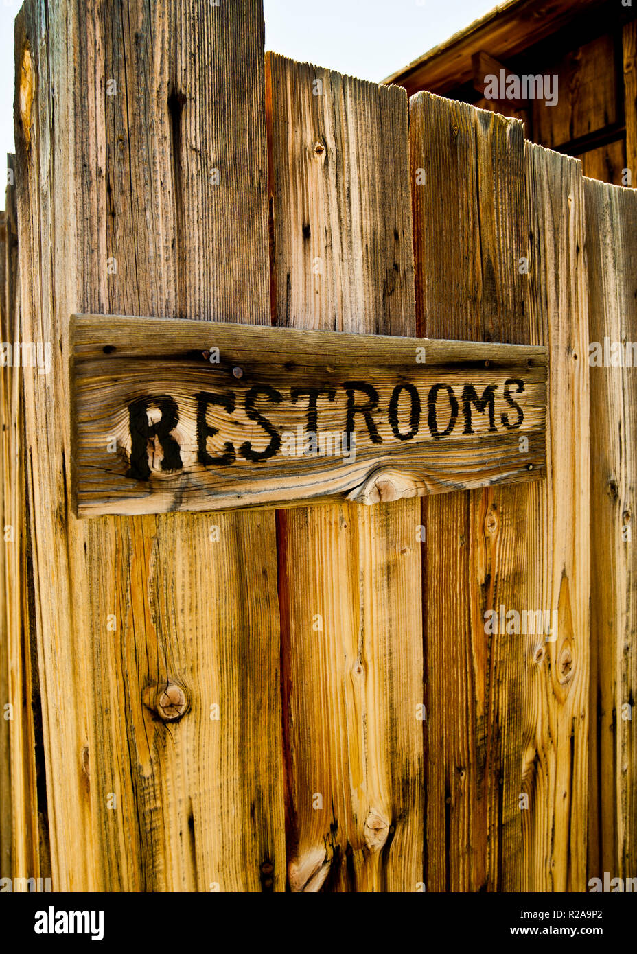 Insegna di bagni fatta da scritta di legno bruciata, montato su vecchi legno nella città fantasma di Bodie, California, USA. Foto Stock