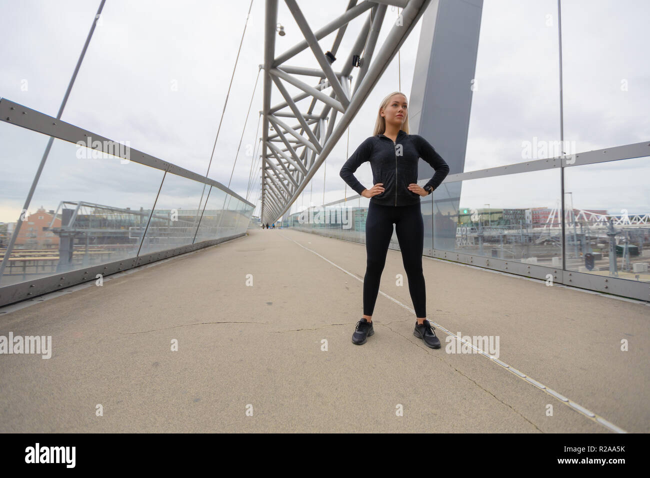 Fiducioso donna con le mani sui fianchi in abito di Allenamento in piedi sul ponte Foto Stock