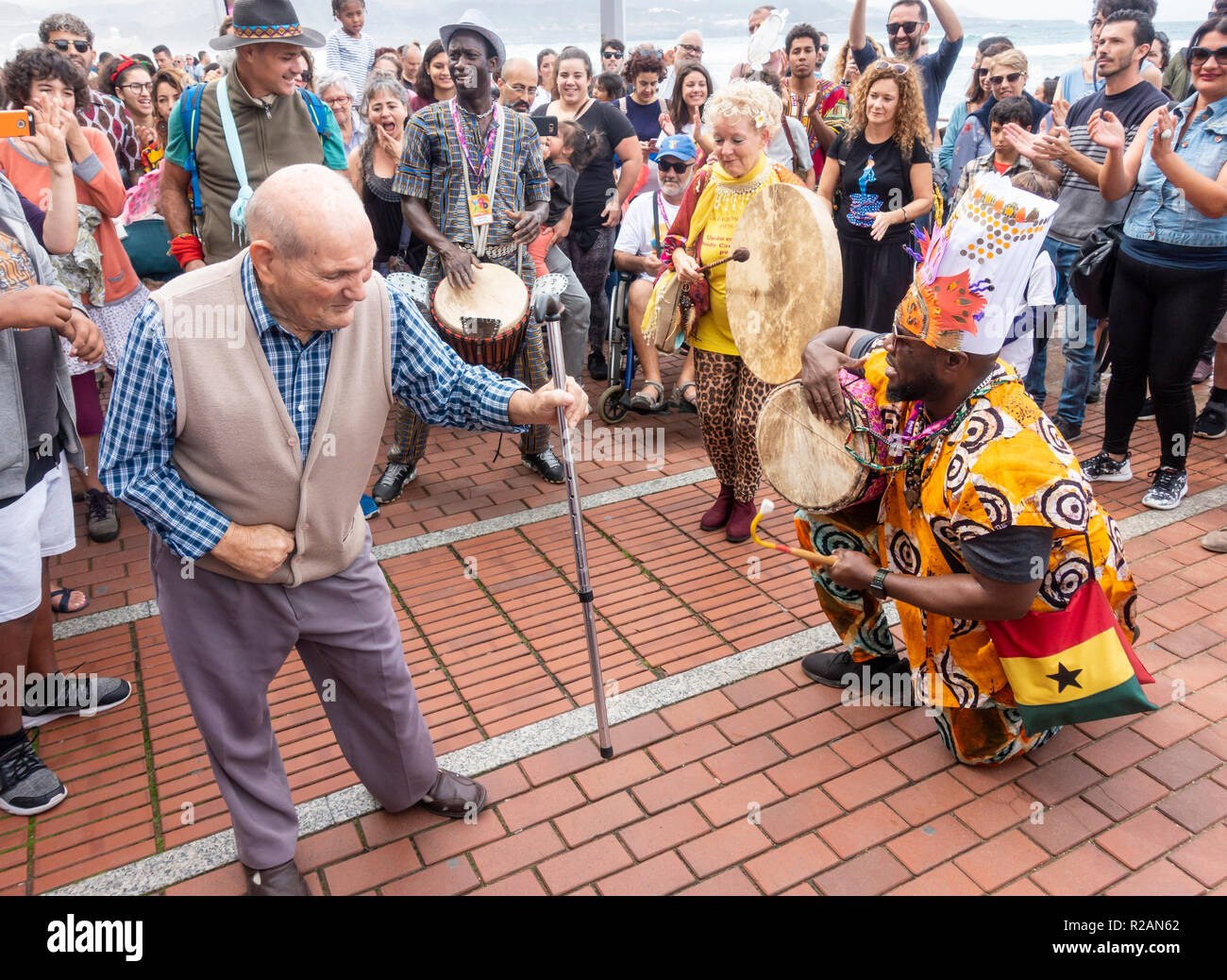 Las Palmas de Gran Canaria, Isole Canarie, Spagna. Il 18 novembre 2018. Un anziano uomo locale viene fuori del suo mobilty scooter e butta giù alcune mosse al Womad Festival di musica di processione di chiusura in Las Palmas. Ex cantante di genesi, Peter Gabriel, è uno dei fondatori di WOMAD. Ora nel suo trentasettesimo anno. WOMAD festivals sono detenute in paesi di tutto il mondo. Credito: ALAN DAWSON/Alamy Live News Foto Stock