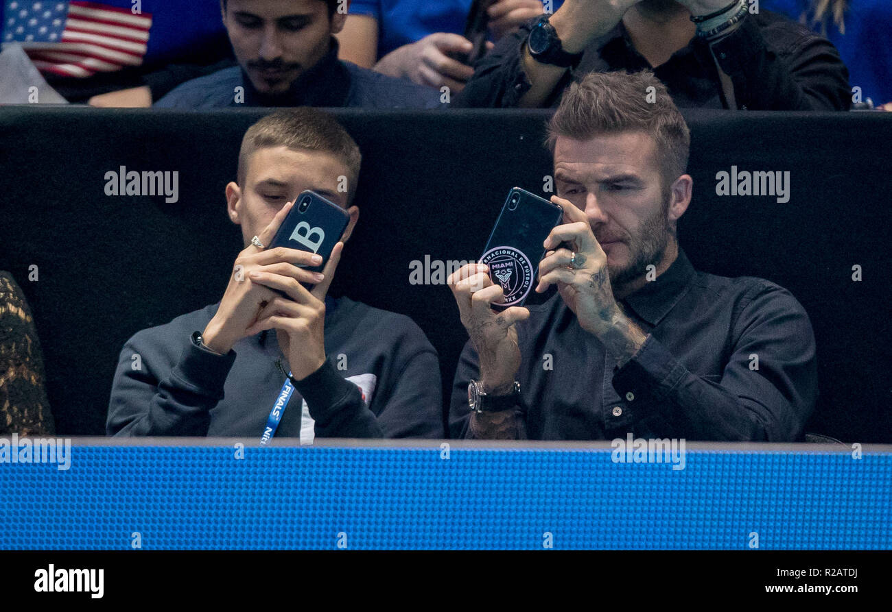 David Beckham guarda la partita attraverso il suo telefono cellulare in cui si ha la sua squadra di calcio Inter Miami del badge su di esso come figlio Romeo Beckham fa lo stesso durante la Nitto ATP Finals London 2018 all'O2, Londra, Inghilterra il 18 novembre 2018. Foto di Andy Rowland. Foto Stock