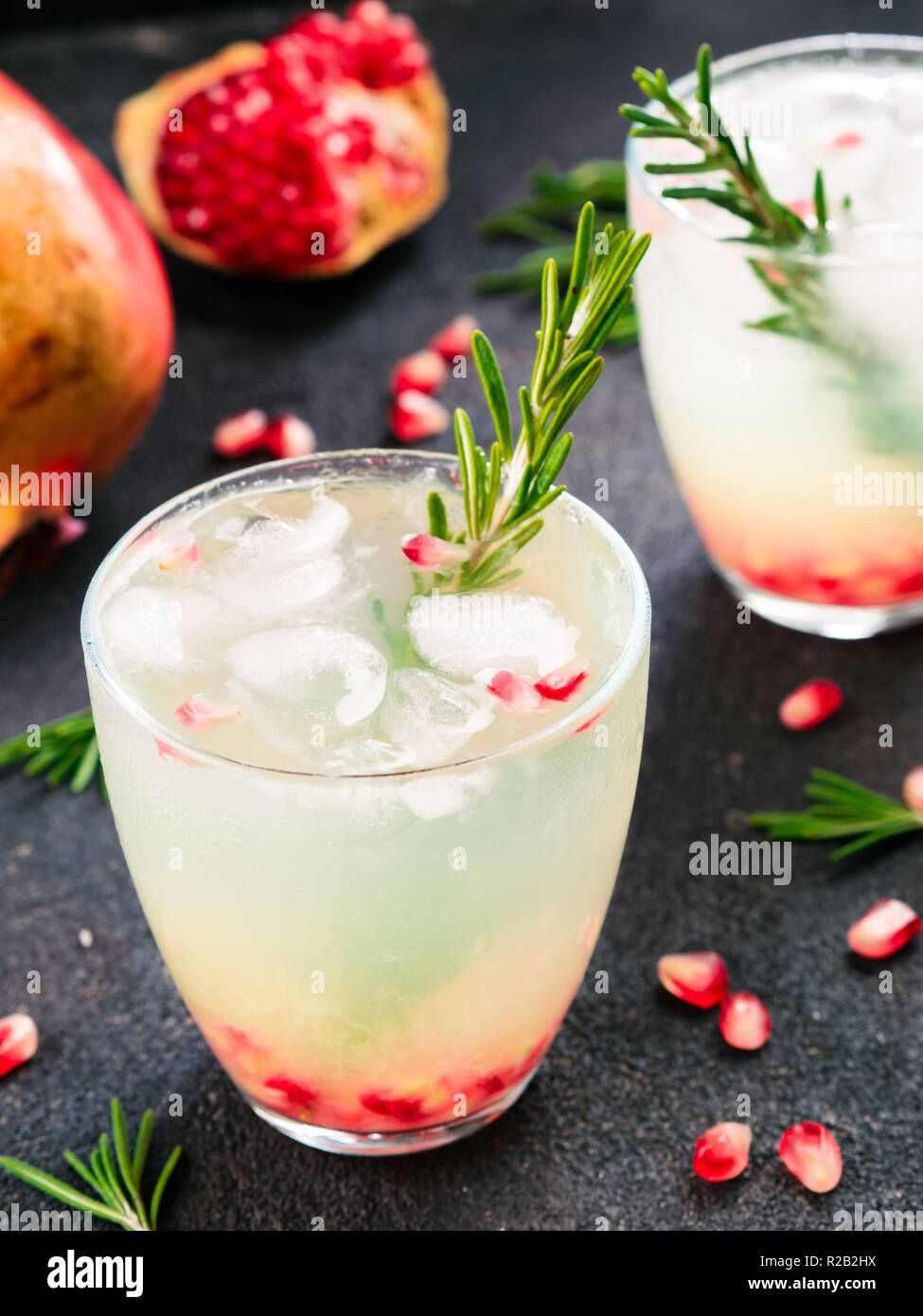 Autunno e Inverno cocktail idea - bianco sangria con rosmarino, pomegrante e il succo di limone e gli ingredienti sul cemento nero lo sfondo. Foto Stock