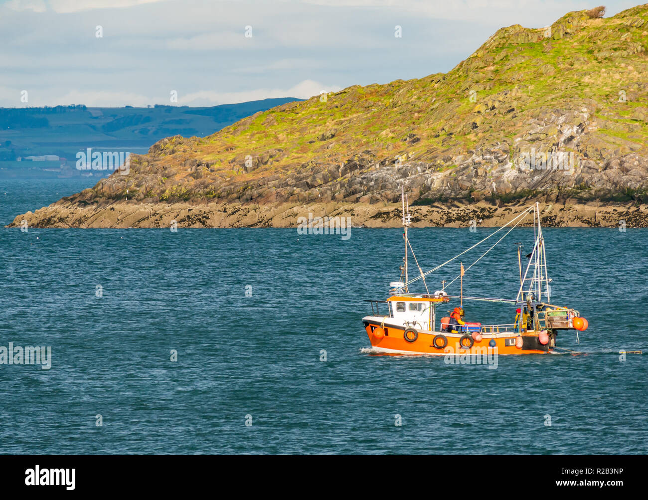 Arancione colorate barche da pesca in mare tra North Berwick e Craigleith Isalnd con uomini e astice pentole sul ponte, Firth of Forth, Scotland, Regno Unito Foto Stock