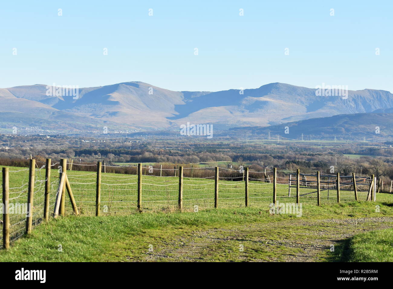 Scena rurale sulla splendida isola gallese di Anglesey. Campi verdi in primo piano e le suggestive montagne di Snowdonia in lontananza. Foto Stock