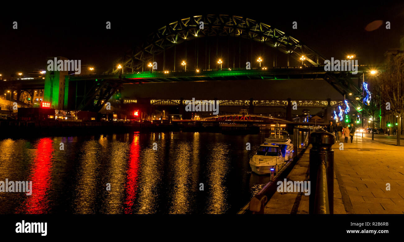Fiume Tyne durante la notte con le luci sul ponte girevole, livello elevato di Bridge e Tyne Bridge e la gente che camminava sul lungofiume, Newcastle, England, Regno Unito Foto Stock