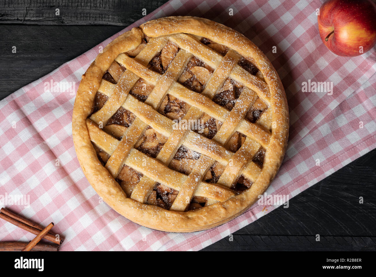 Al di sopra di vista di una deliziosa casa torta di mele con un reticolo crosta, su un asciugamano rosa, su di un tavolo di legno. Pane appena sfornato dolci. Torta nazionale il giorno. Foto Stock