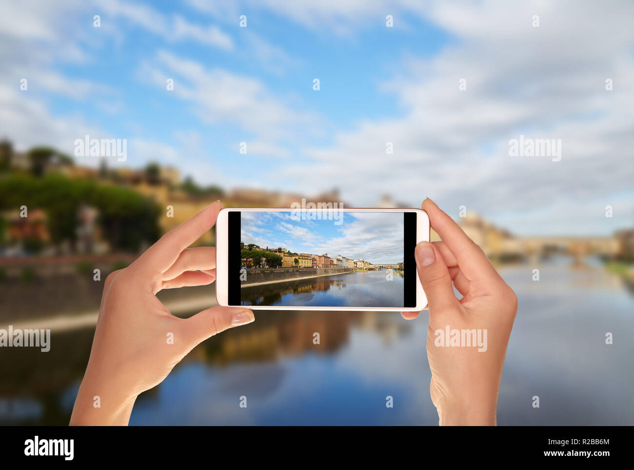 Un turista è di scattare una foto di banchina del fiume Arno e Ponte Vecchio a Firenze, Italia su un telefono cellulare Foto Stock