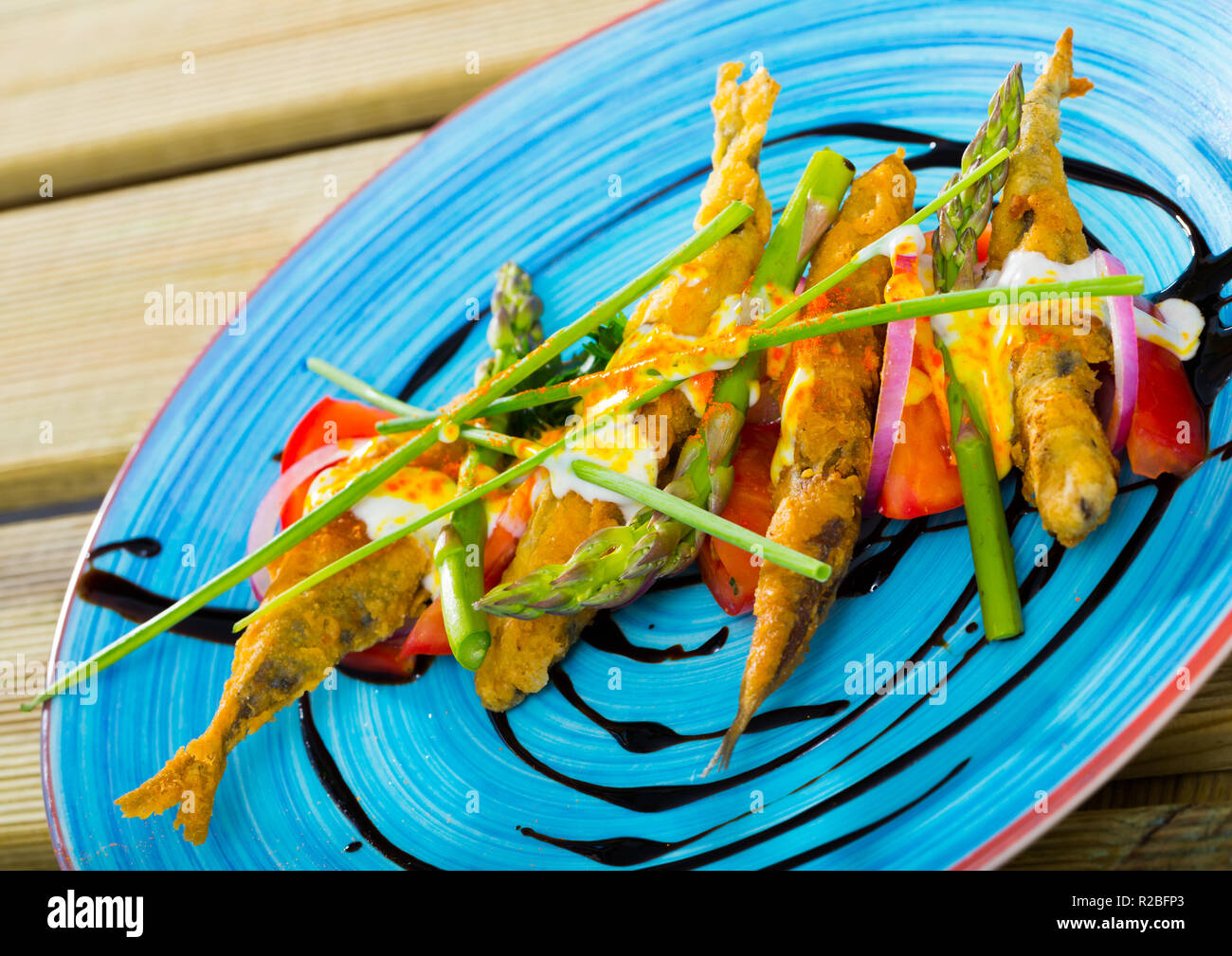 Sardine fritti in pastella con cremosa salsa di zenzero sul cuscino di pomodori dolci e pasta di aceto balsamico Foto Stock