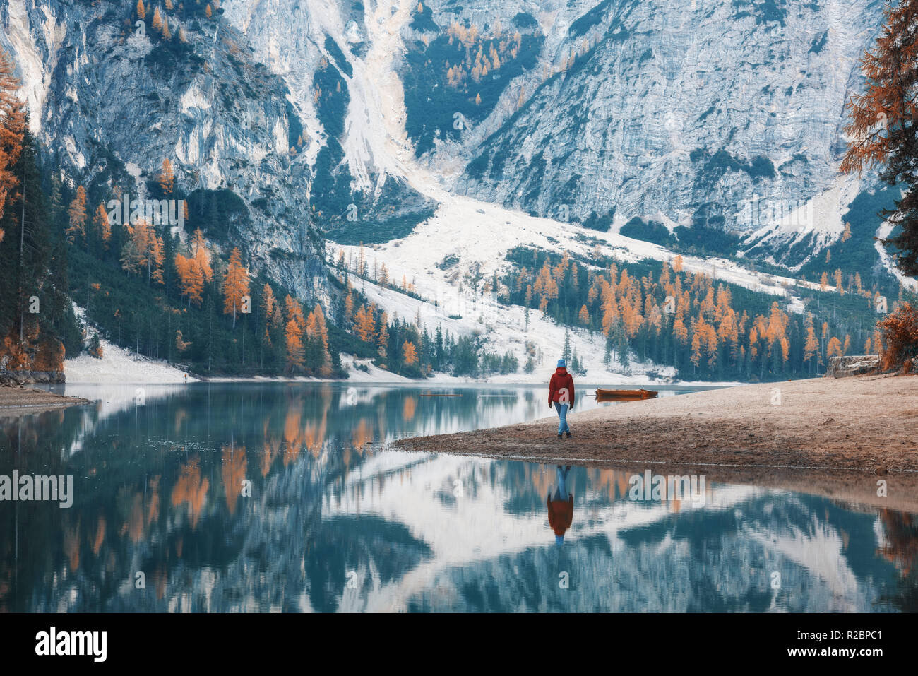 Donna in piedi sulla costa del lago di Braies al mattino in autunno. Dolomiti, Italia. Paesaggio con ragazza, il famoso lago con bella riflessione in w Foto Stock