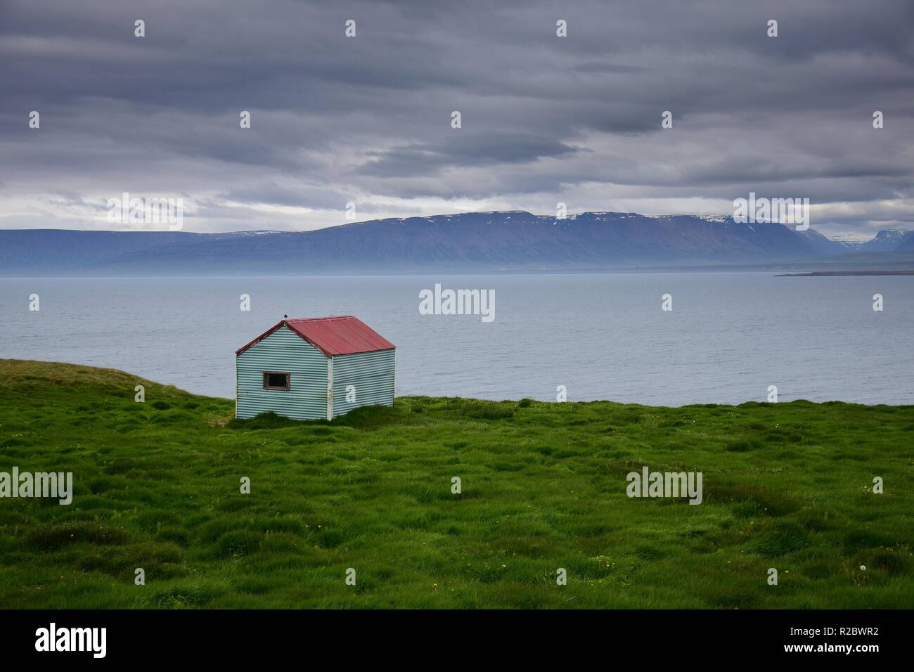 Paesaggio islandese. Una capanna di stagno all'oceano con un tetto rosso. Penisola Skagi, Skagafjördur. Foto Stock