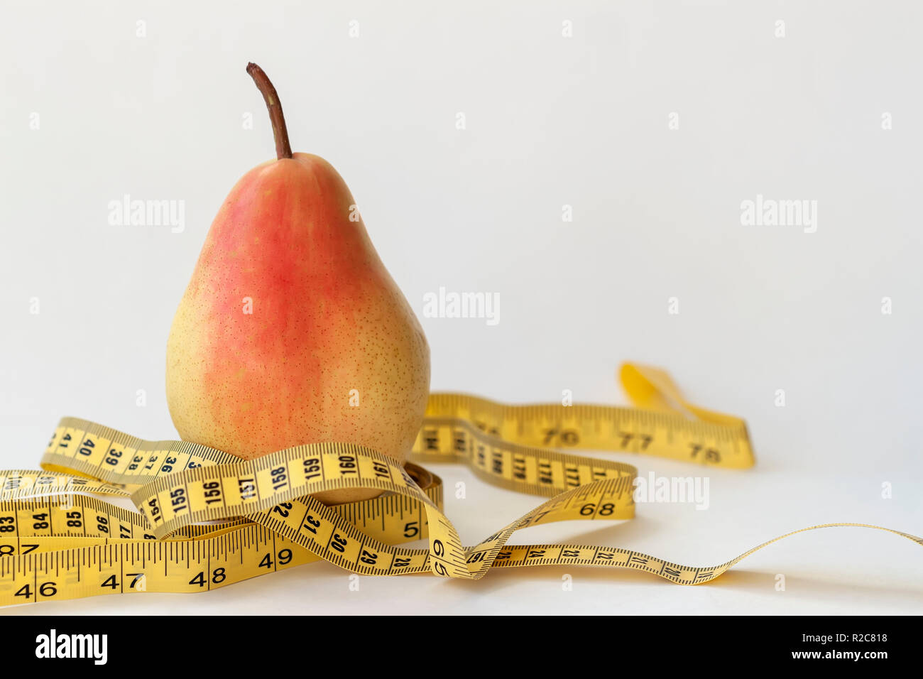 Giallo maturo pera e nastro di misurazione su sfondo chiaro, il concetto di uno stile di vita sano, dieta Foto Stock