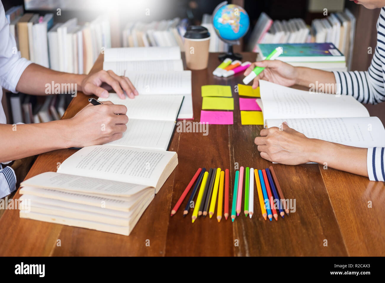 Giovani studenti compagni di aiutare un amico a recuperare la cartella di lavoro e tutoraggio di apprendimento in una libreria, l educazione e il concetto di scuola. Foto Stock