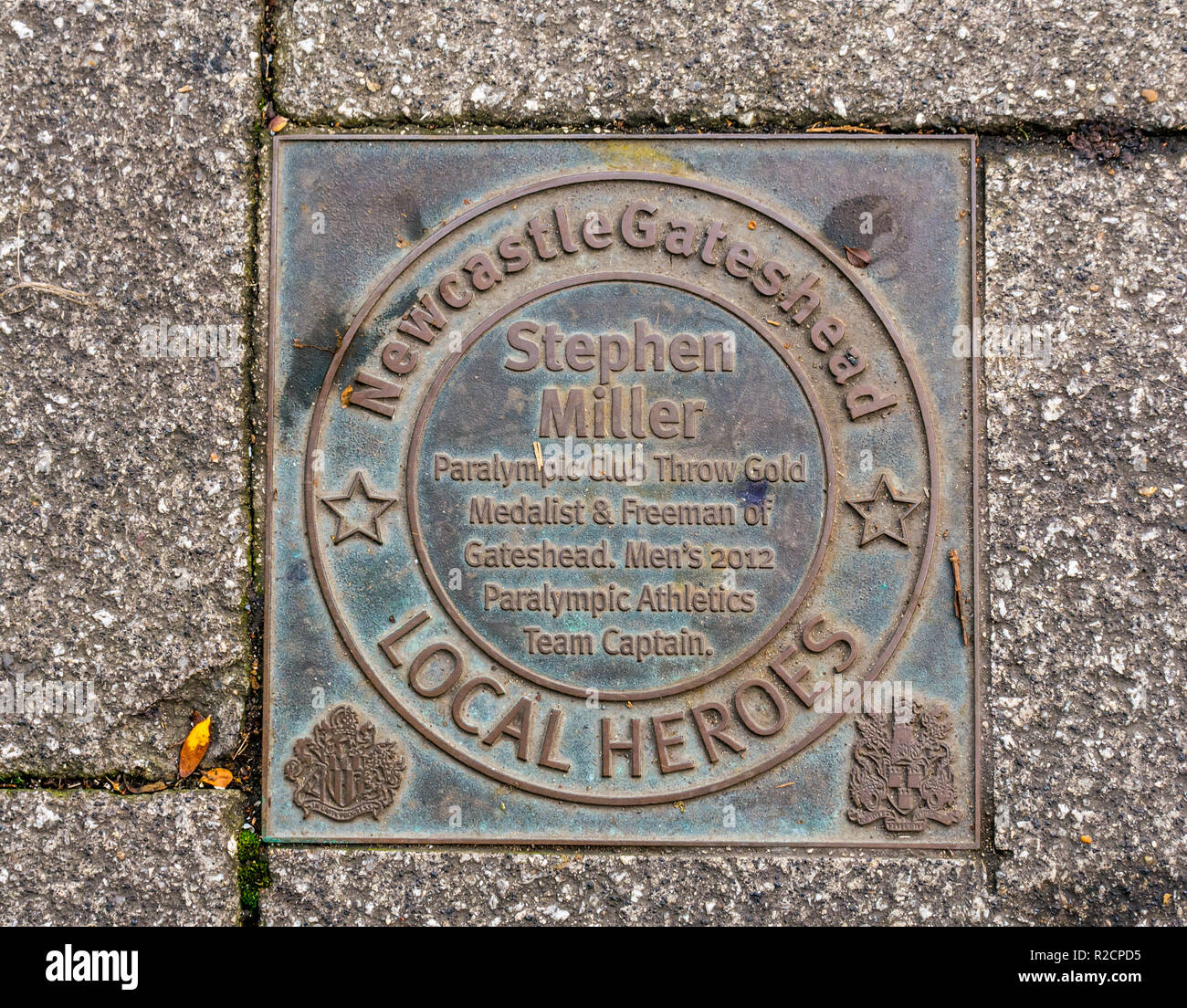 Targa di bronzo in onore di Newcastle Gateshead e ispirare le persone di 60 anni passati, Stephen Miller, Quayside. Newcastle Upon Tyne, England, Regno Unito Foto Stock