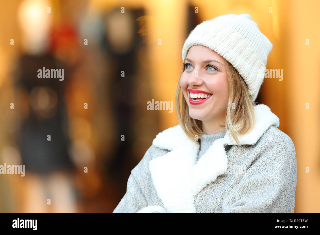 Donna felice pensare guardando sopra in piedi in un centro commerciale di inverno Foto Stock