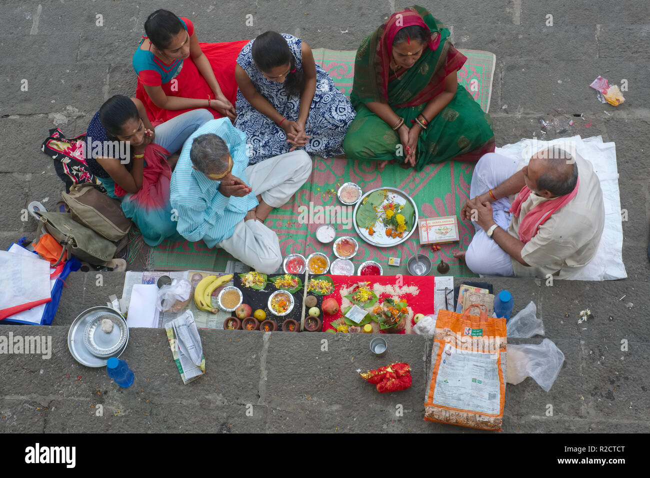 Un sacerdote al serbatoio Banganga in Mumbai, India, conduce il memorial riti di una famiglia del defunto socio, offerte sacrificali stesa per terra Foto Stock