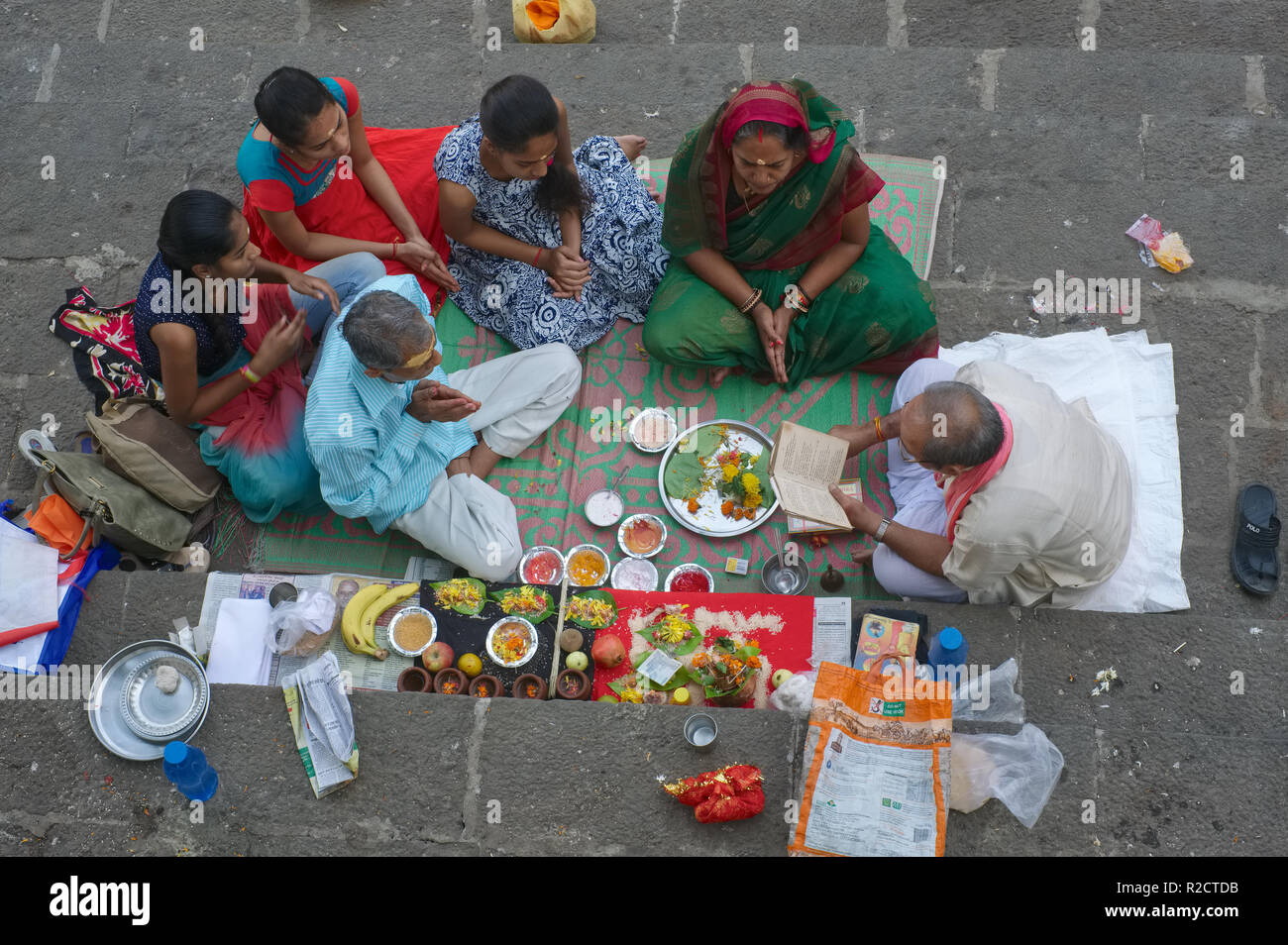 Un sacerdote al serbatoio Banganga in Mumbai, India, conduce il memorial riti di una famiglia del defunto socio, offerte sacrificali stesa per terra Foto Stock