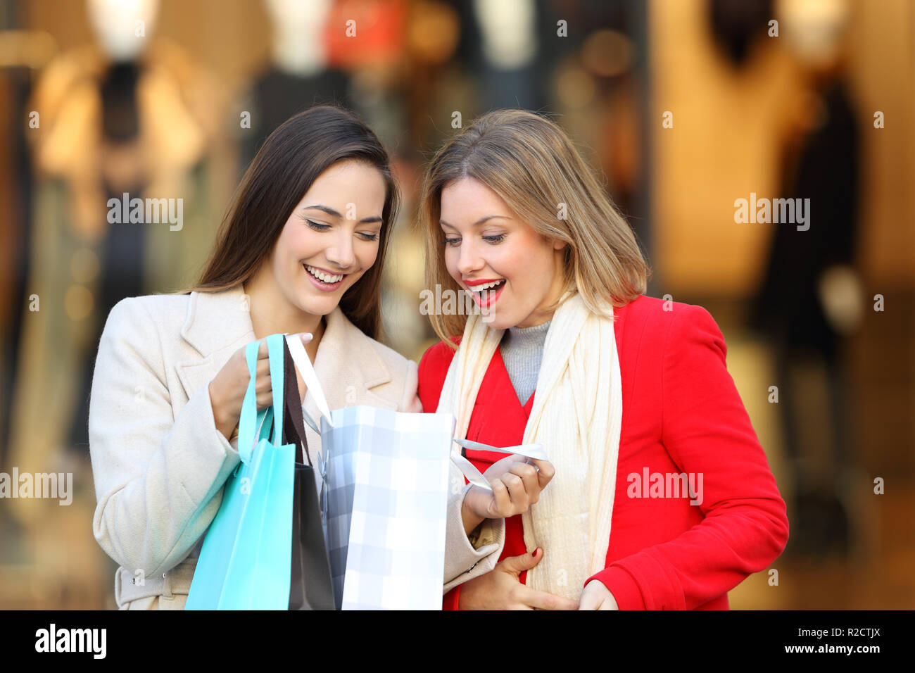 Vista frontale di due acquirenti felici controllo degli acquisti in un fatto shopping bag in un centro commerciale Foto Stock