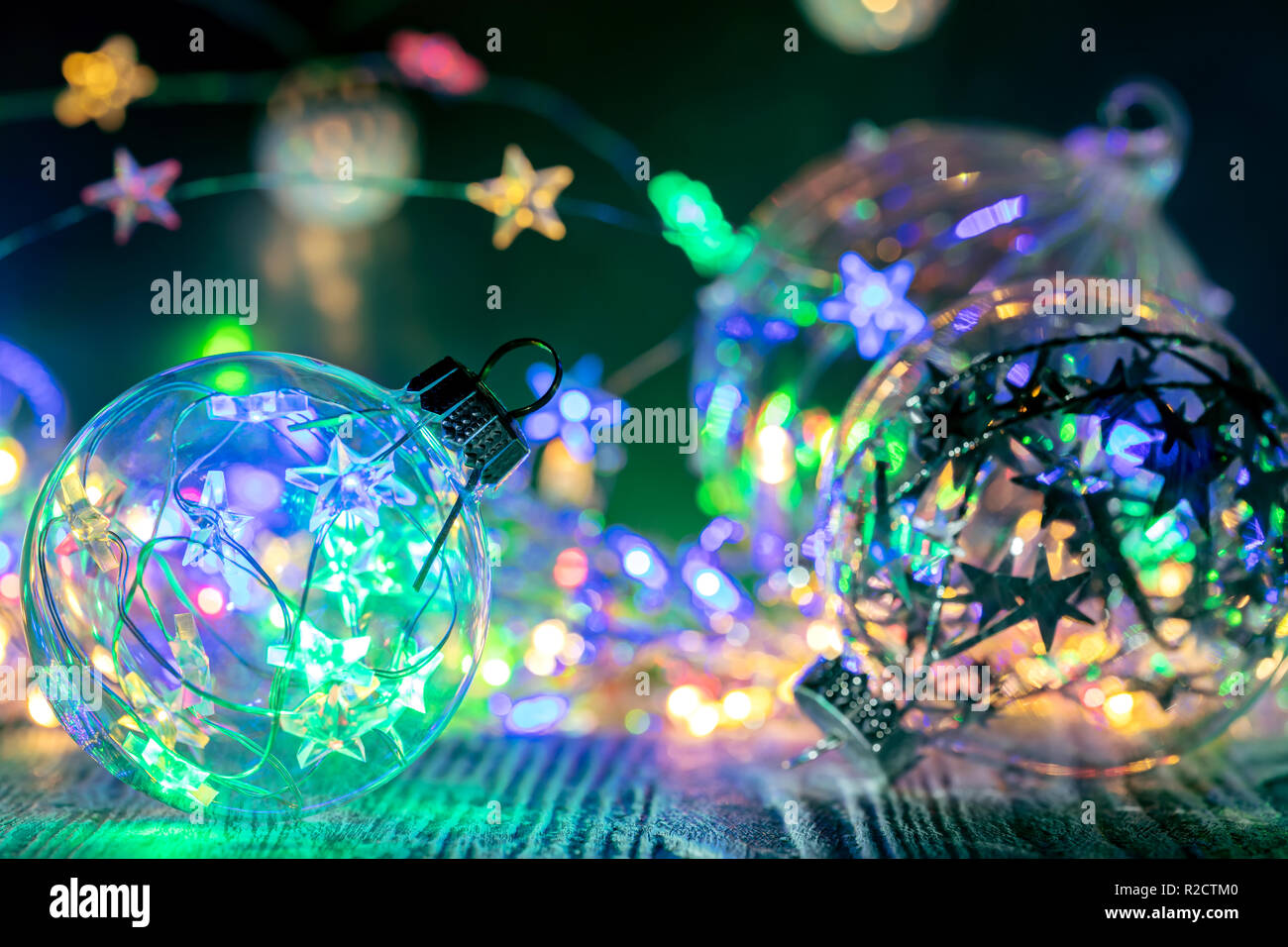 Albero di natale di vetro decorativo contro le sfere colorate di festa luci incandescenti sfondo Foto Stock