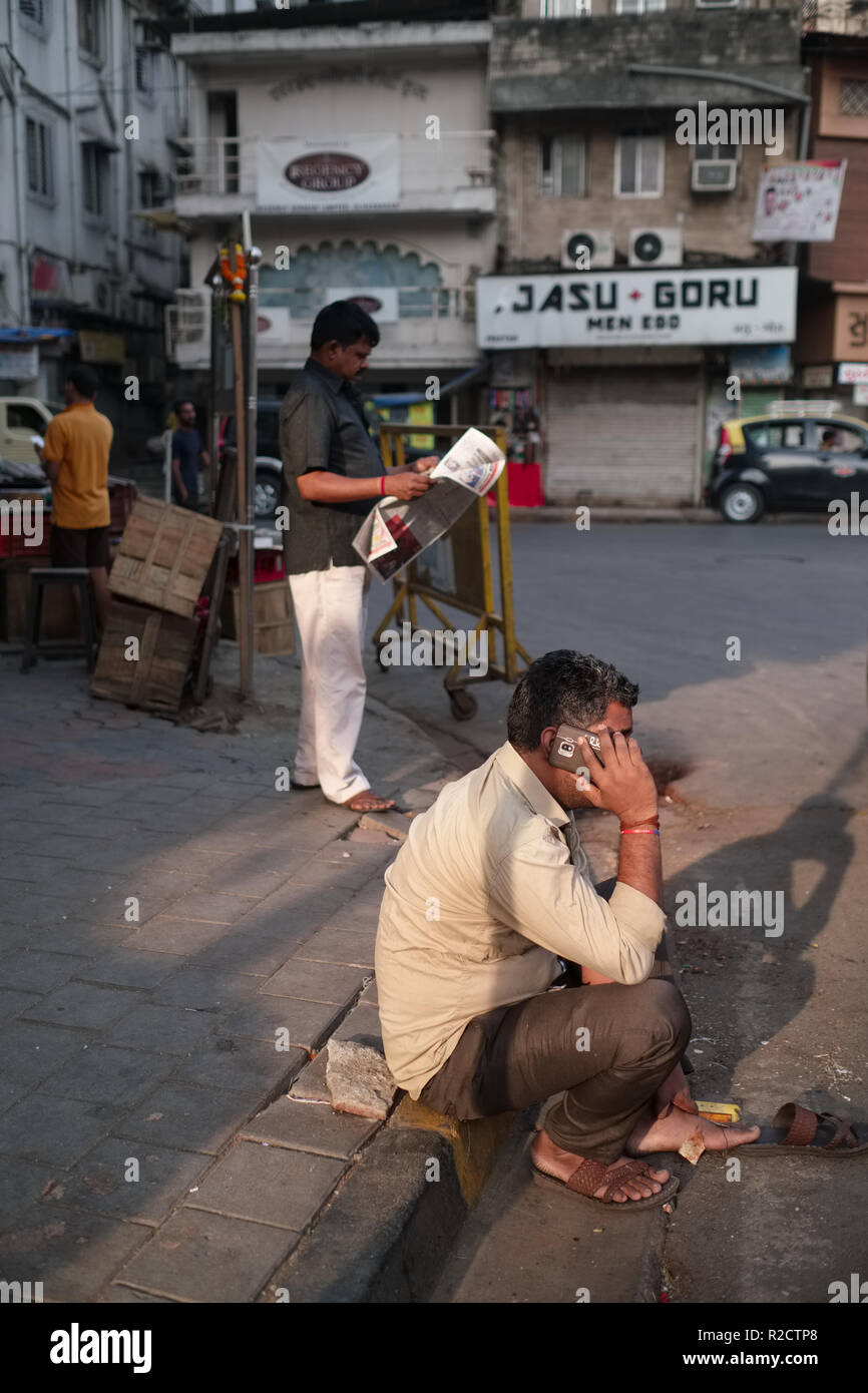 Un uomo nell'area business di Bhuleshwar in Mumbai, India, parlando sul suo telefono cellulare, per l'adozione di un "mondo rurale di tipo a posizione accovacciata Foto Stock