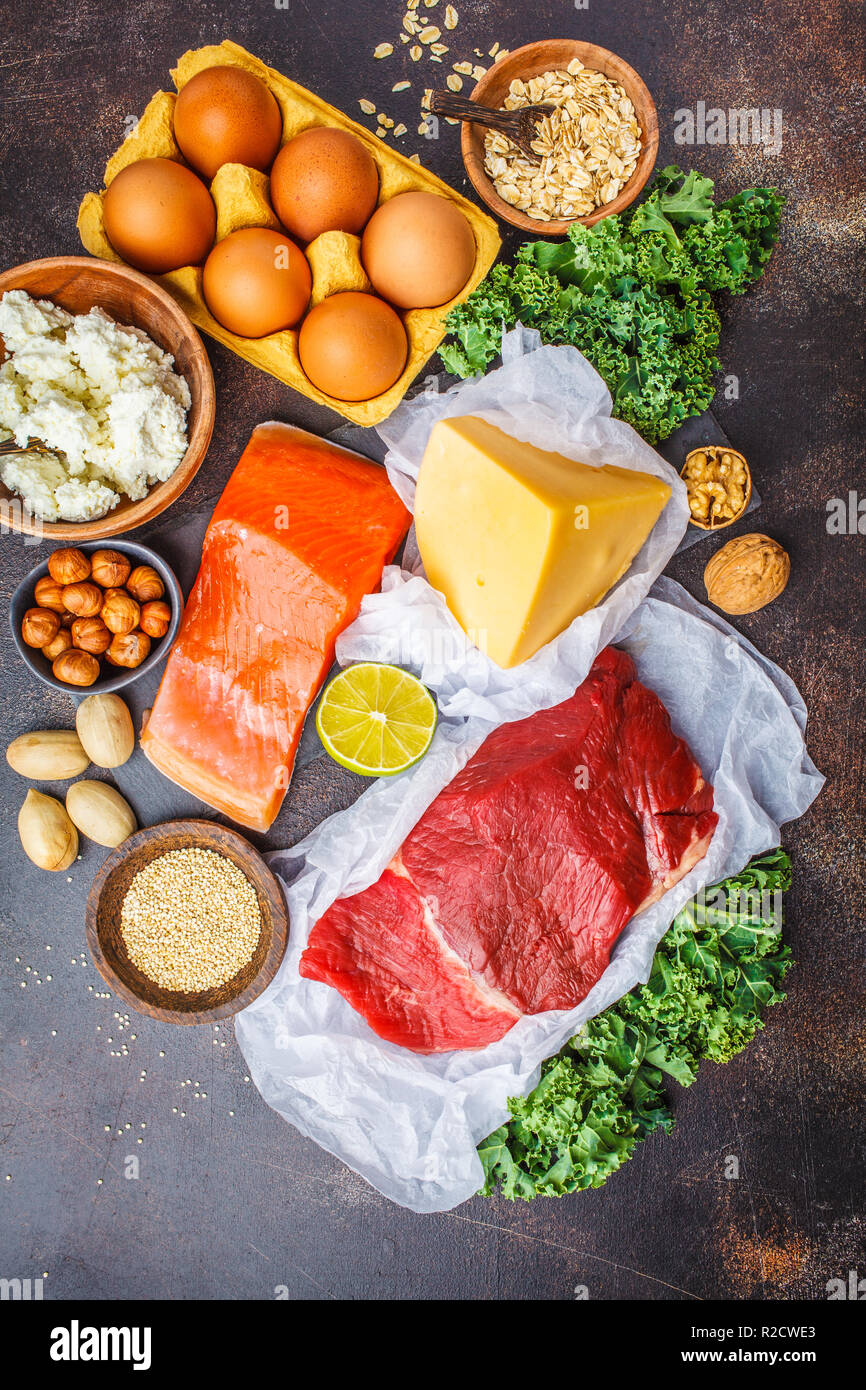Dieta bilanciata cibo sfondo. Alimenti proteici: pesce, carne, uova, formaggio, quinoa, dadi su sfondo scuro, vista dall'alto. Foto Stock