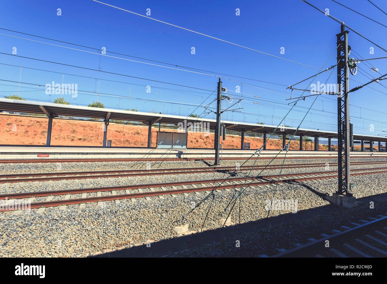 Binari del treno con la catenaria di overhead e linee elettriche in un cielo blu di sfondo, alla stazione di Cuenca Foto Stock