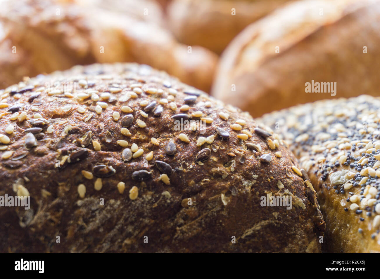 Close-up di miste di pane e pasta di pane cotto al forno rotoli utilizzabili come cibo decorativo sullo sfondo. Pane appena sfornato in grani interi rotoli di pane con semi di sesamo. Foto Stock
