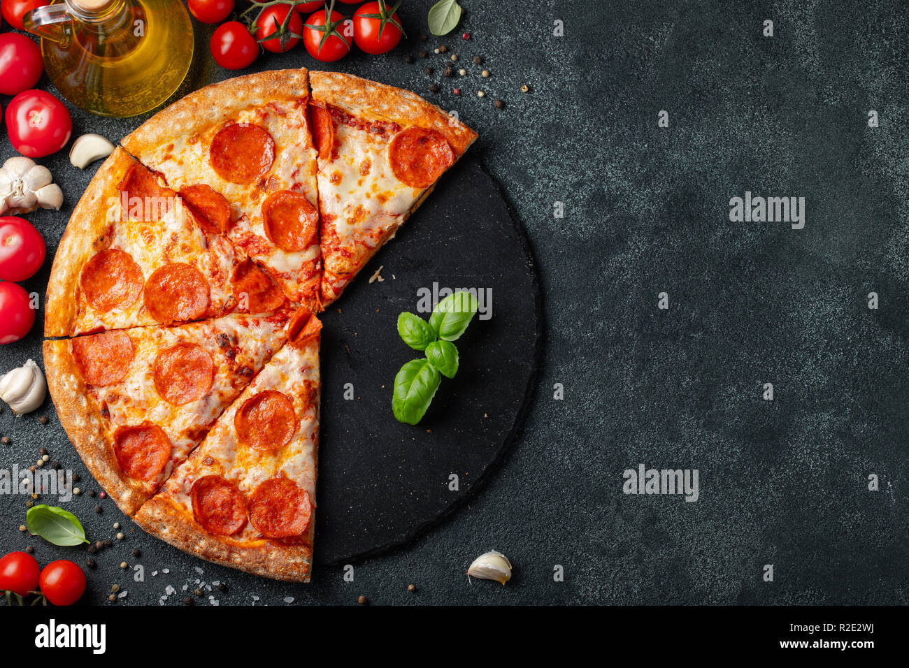 Gustosa salsiccia per pizza pizza e cottura Ingredienti Pomodori basilico nero su sfondo di calcestruzzo. Vista superiore della salsiccia per pizza calda pizza. Copia con spazio per il testo. Foto Stock