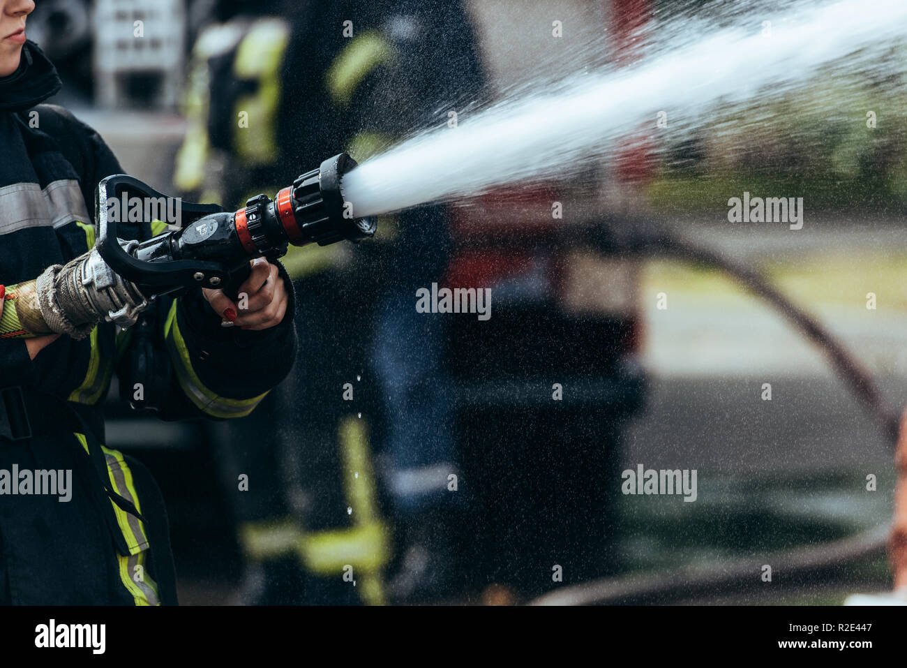 Vista parziale del vigile del fuoco con tubo flessibile di acqua di spegnimento incendio sulla strada Foto Stock