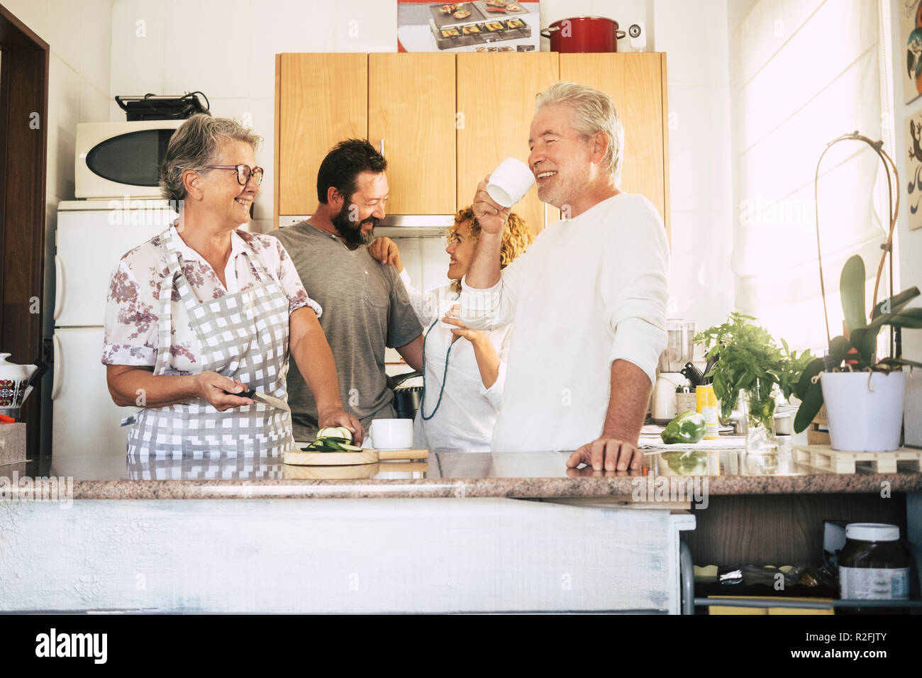 Famiglia con due differenti età giovane tutti insieme in amicizia e relazione in cucina nella preparazione degli alimenti e il pranzo a casa. La vita reale e la gente nel lavoro quotidiano. allegro stile di vita felice caucasico per le donne e gli uomini Foto Stock