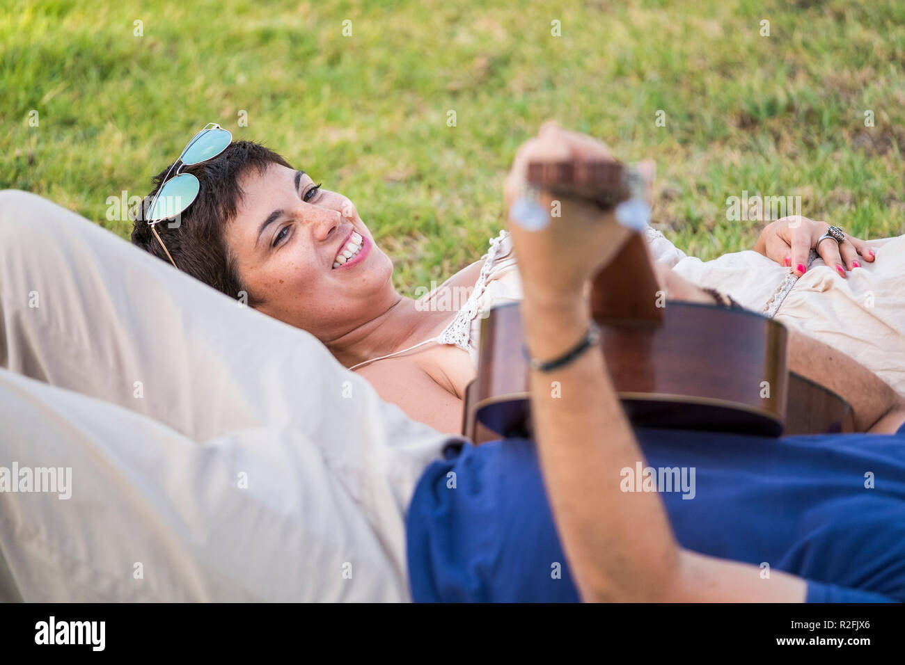 Coppia romantica l uomo e la donna adulti senior a suonare la chitarra in una serenata per amore e relazioni. Focus sulla bella faccia allegra della giovane donna sorridente per l'uomo. Stabiliscono e rilassante di persone Foto Stock