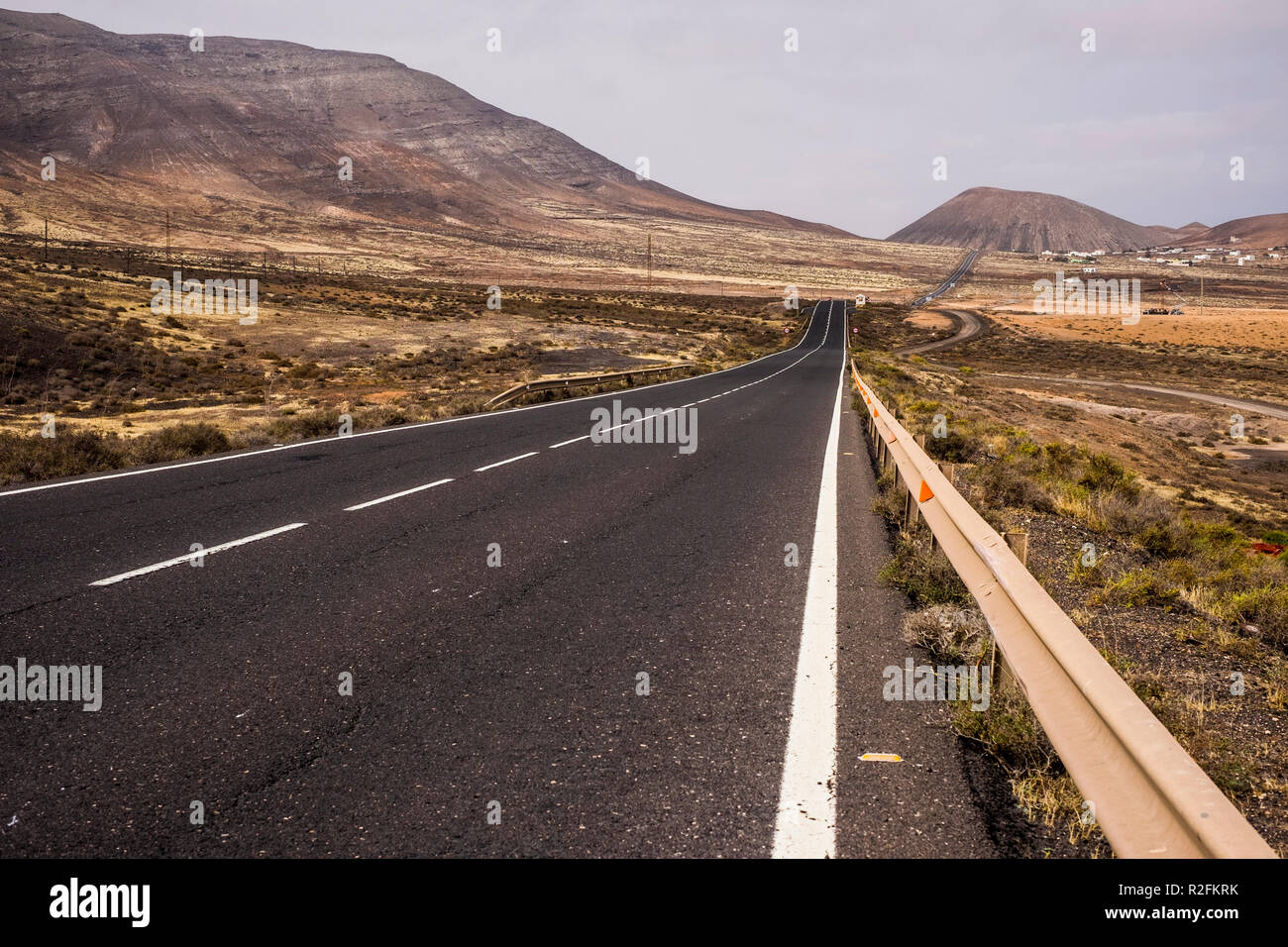 Lunga strada dritta strada nel mezzo di un nessuno ci paesaggio in fuerteventura per attraversare l'isola e spostare. alternativa allo stile di vita del vento che vivono in palce dove nessuno altro soggiorno. spirito di avventura godendo il viaggio Foto Stock