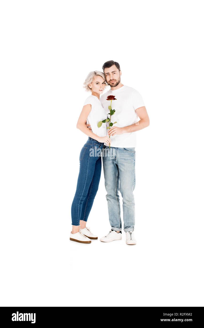 Attraente giovane adulto giovane con fiore abbracciando mentre guardando la telecamera isolato su bianco Foto Stock