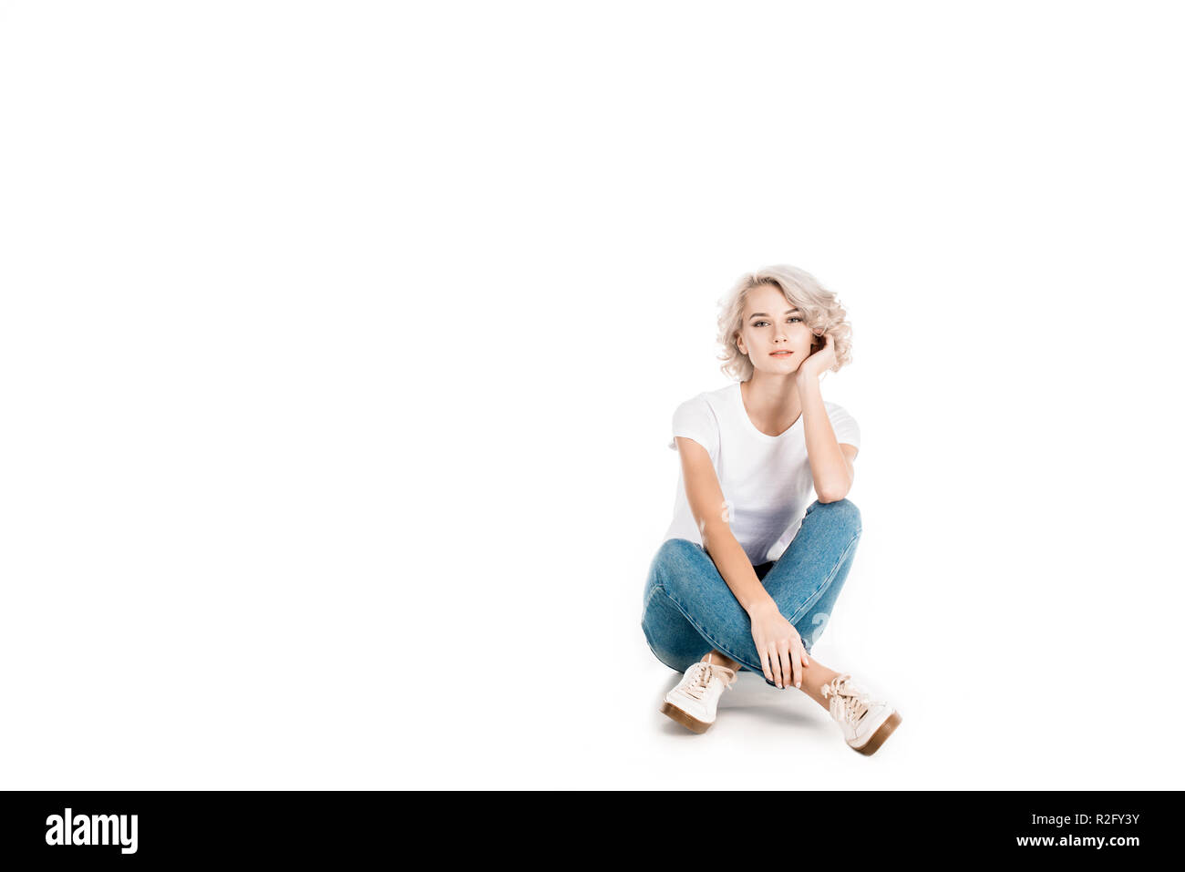 Attraente bionda giovane adulto donna seduta isolato su bianco Foto Stock