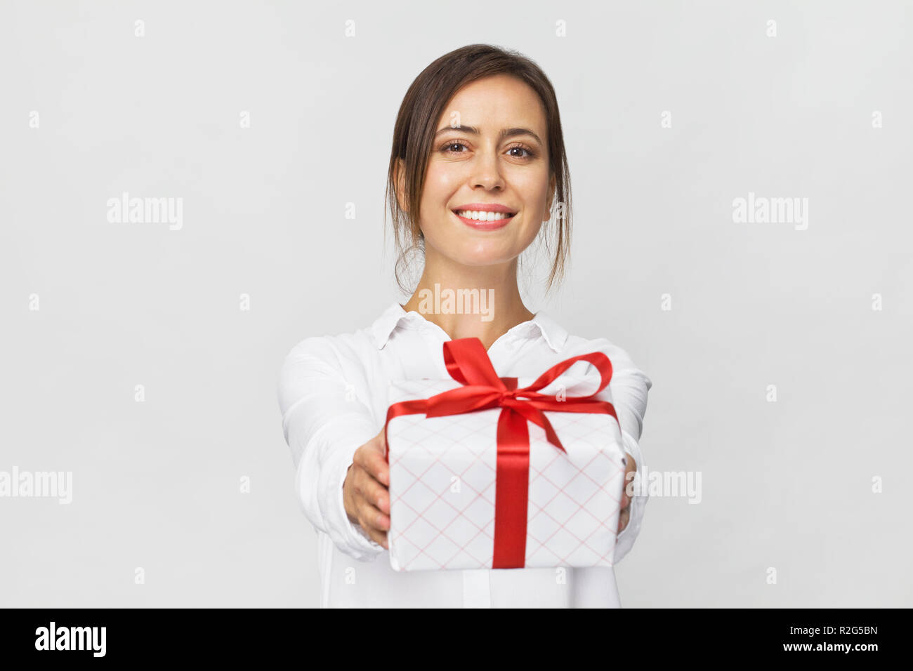 Bella donna tenendo una confezione regalo con un nastro rosso. Isolato su sfondo bianco Foto Stock